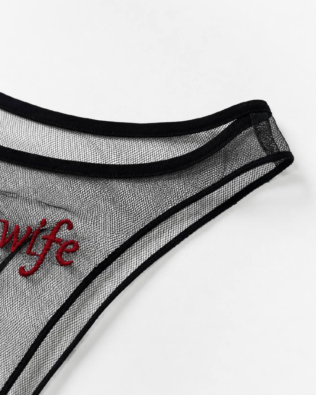 Close-up of black sheer mesh and red Hotwife embroidery