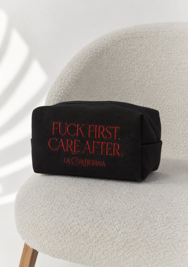 Fuck First Care After embroidered black pouch on a soft chair