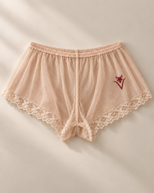 Frau trägt hauchdünne Schlafshorts aus transparentem, hautfarbenem Netzstoff mit individueller roter Stickerei von La Cortigiana